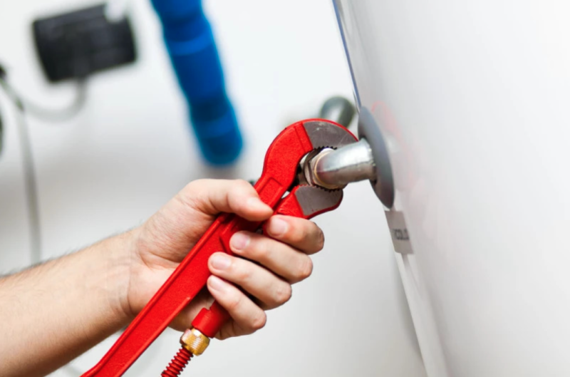 person using wrench on hot water heater