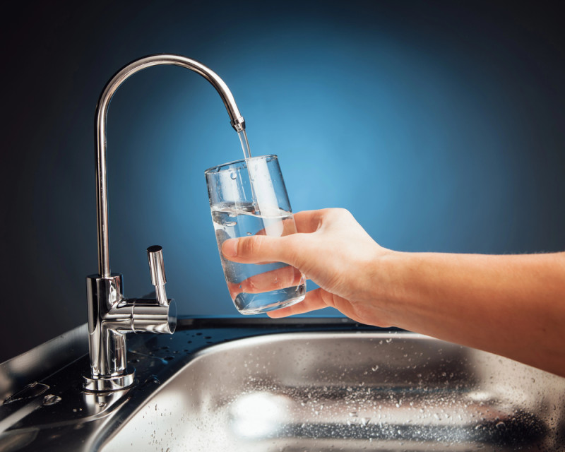 person using water filter to fill glass of water