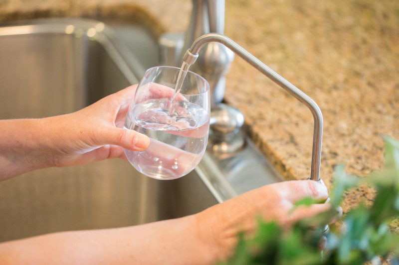 Person pouring water into glass from water filter